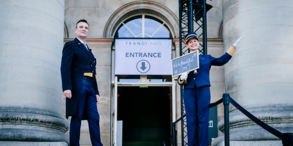 Two people in uniform point out the entrance.